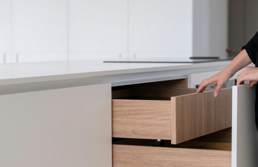 Myway: Détail de finitions sur mesure : tiroirs de cuisine en bois intégrés dans un îlot blanc minimaliste.